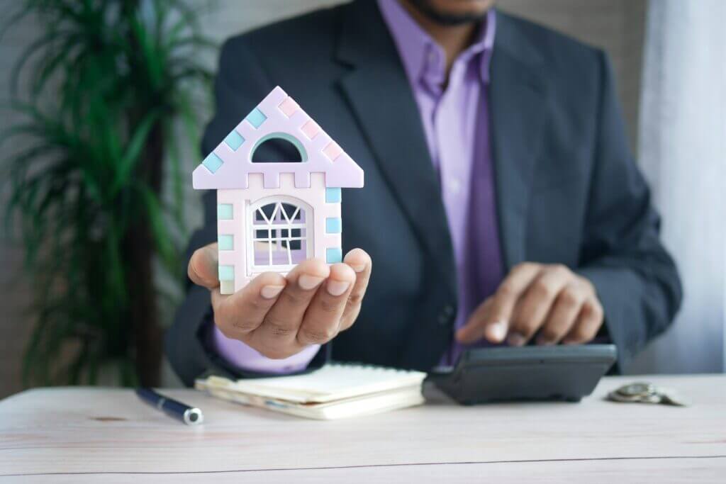 an imaging of a man holding a small home depicting mortgage interest relief.